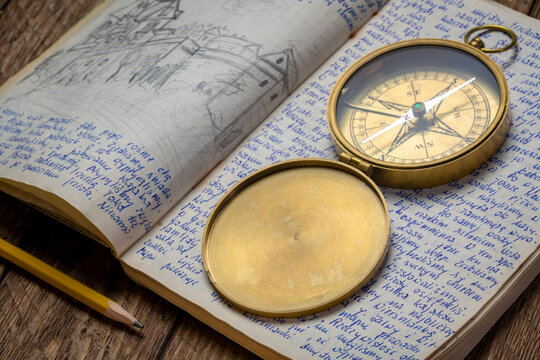 Vintage travel journal with handwriting and pencil sketches and old brass compass.