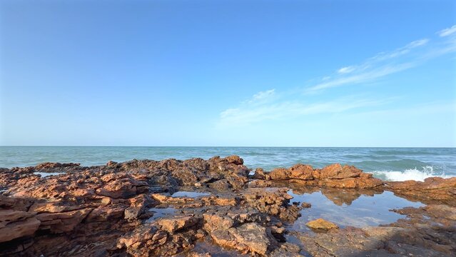 Rocky shoreline with calm sea under clear blue sky