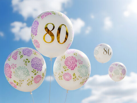 White balloons with gold 80 and floral patterns floating in blue sky.