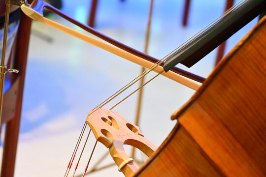 Nahaufnahme einer Person, die ein Cello mit einem Bogen spielt.