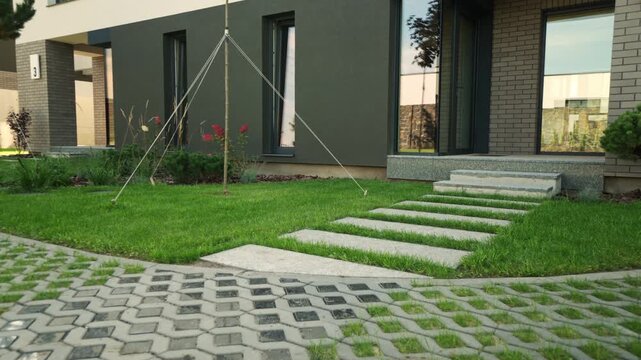 Modern house exterior with eco-friendly turf block paver driveway, green lawn, stone path