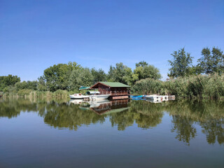 Obraz premium Traditional Wooden Houseboat and Small Boats Docked on Calming River Surface