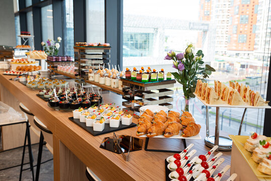Buffet table with assorted sandwiches, croissants, desserts, and appetizers for event catering and corporate party design