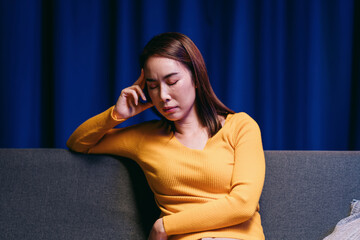 Obraz premium Stressed Asian Woman Feeling Headache on Sofa Suffering Depressi