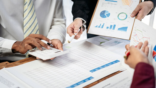A group of people are looking at a table with graphs and charts