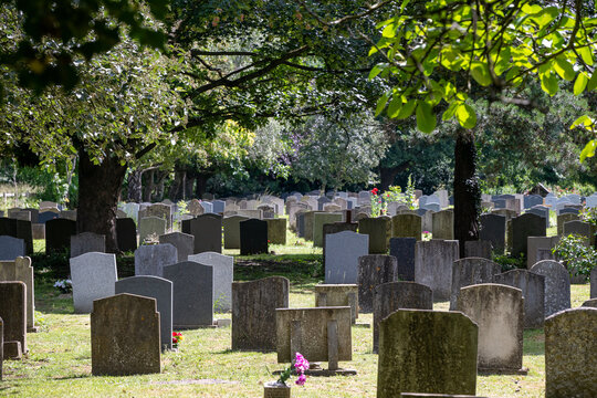 Rows of old headstones and graves in the churchyard cemetery of St Nicholas Church, Ashchurch, Gloucestershire, England