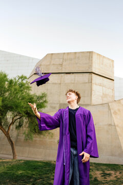 Young male graduate throwing cap in the air
