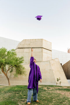 Young man in cap and gown, throwing cap in the air