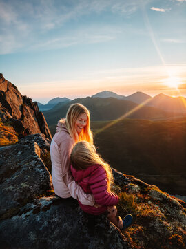 Family mother and daughter enjoying sunset view hiking in mountains of Norway together, parent and child having fun outdoor people on active summer vacations camping trip in the wild, candid emotions