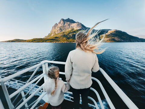 Mother and daughter travel by ferry in Norway with sea and island view, parent and child on summer vacations voyage tour sightseeing and exploring Arctic nature together