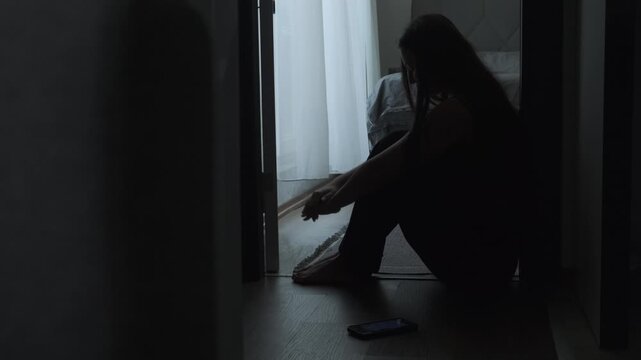 Woman sitting alone in the dark after messaging, feeling ignored and ghosted. Concept of digital heartbreak and loneliness online