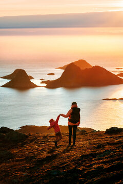 Family travel summer vacations in Norway mother hiking with child, parent and kid having fun outdoor in mountains enjoying sunset sea and islands view backpacking trip happiness emotions togetherness