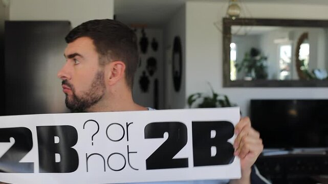 Man holding "TO BE or not TO BE" sign