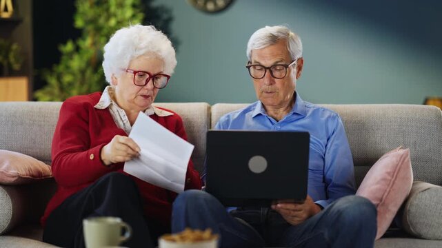Senior partners reviewing invoices, statements or account information using a laptop. Financial planning, budgeting and technology adoption.