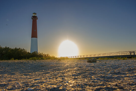 Barnegat Lighthouse at golden hour with sunburst over the beach