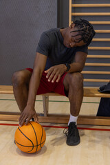 Naklejka premium Basketball is resting on polished wooden court beside bench with folded towel and stall-bar