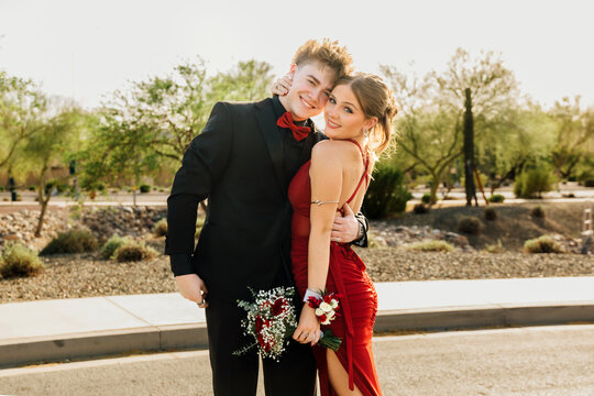Prom dates hugging in street, dressed up