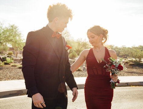 Prom dates holding hands in street
