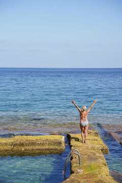 Senior woman celebrating freedom by the sea