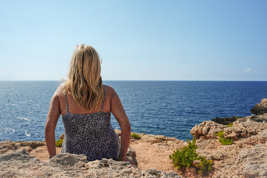 Senior woman sitting by the sea during vacation