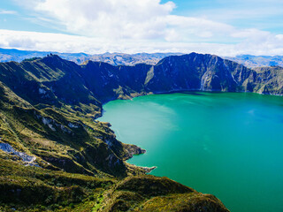 Obraz premium Breathtaking aerial view of the turquoise Quilotoa volcanic crater lake nestled within the dramatic mountainous landscape of the Ecuadorian Andes