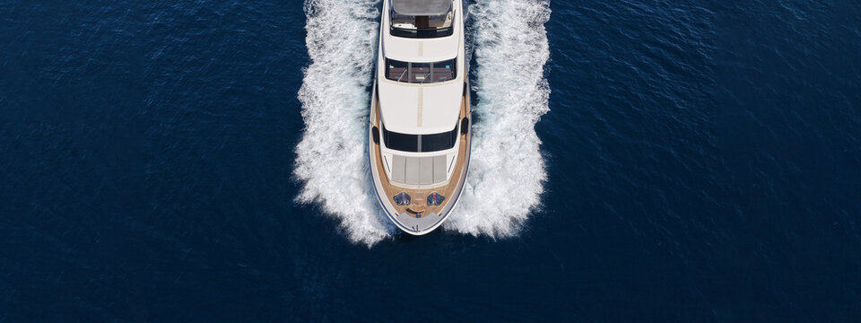 Aerial drone ultra wide photo with copy space of luxury yacht with wooden deck cruising in high speed deep blue Aegean sea