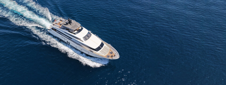 Aerial drone ultra wide photo with copy space of luxury yacht with wooden deck cruising in high speed deep blue Aegean sea