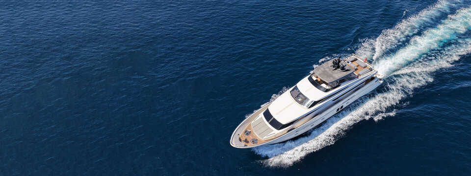 Aerial drone ultra wide photo with copy space of luxury yacht with wooden deck cruising in high speed deep blue Aegean sea