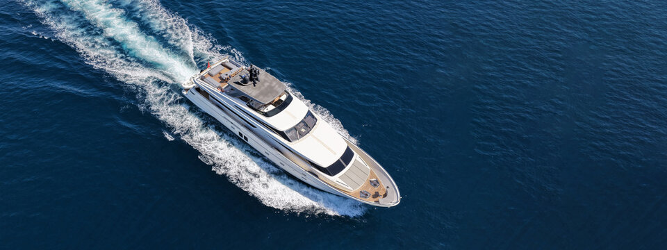 Aerial drone ultra wide photo with copy space of luxury yacht with wooden deck cruising in high speed deep blue Aegean sea