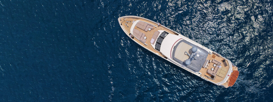 Aerial drone ultra wide panoramic photo with copy space of luxury yacht with wooden deck anchored near port of Port of Fontvieille in deep blue sea, Monaco, France
