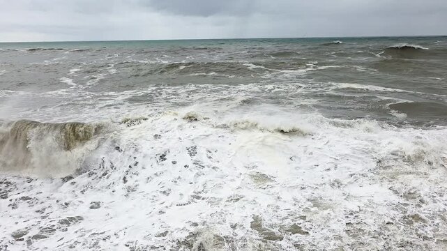 Sea surge sounds. Swelling ocean thrashing with frothy waves. Turmoil at sea with frothing waves and misty spray. Raging ocean surface surging with foam and spray amid turbulent waters