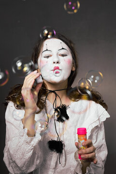 Clown woman with closed eyes blowing soap bubbles in dreamlike portrait