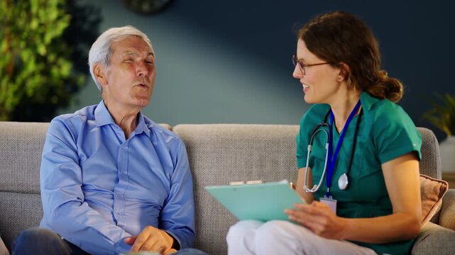 A doctor reviews a patient's health details during an appointment. The patient sits on a couch while the doctor takes notes and asks questions about their health and concerns.