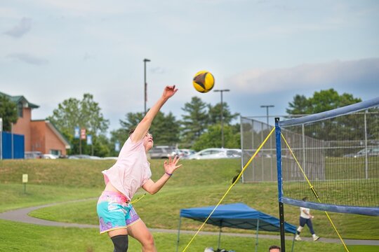 Volleyball player hitting yellow ball over the net