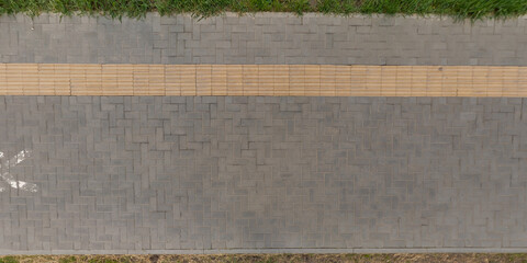 Fototapeta premium top view of surface of pedestrian path with paving slabs with the border of light and shadow