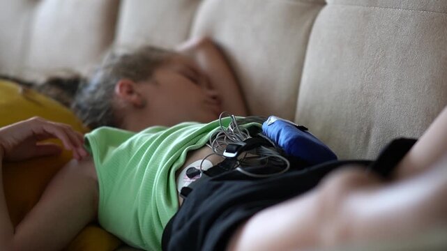 close up of girl with medical equipment undergoing heart examination. Heart monitoring. Girl with heart monitor resting on sofa