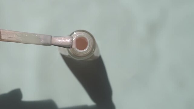 Glossy nail polish spilled on the surface. Brush and glass bottle for polish.