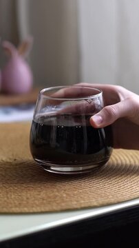 A child's or teenager's hand places a glass of carbonated, sweet drink on the table. A refreshing drink in a cup. High quality FullHD footage