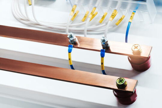 Copper high-voltage electrical busbars run horizontally along the frame, and electrical wires are connected to them. Metal terminals securely hold the connections. Industrial concept.