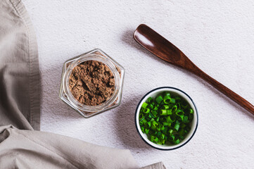 Fototapeta premium Liver pate in a jar and green onions in a bowl on the table top view