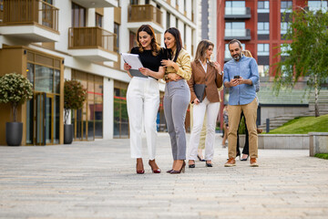 Fototapeta premium Business colleagues walking and discussing documents outside modern office building