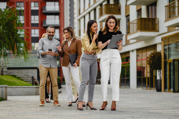 Fototapeta premium Business colleagues walking and discussing documents outside a modern office building during a casual team meeting