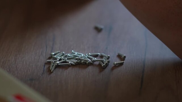Wooden furniture pegs scattered on the surface of the chipboard. Furniture assembly at home