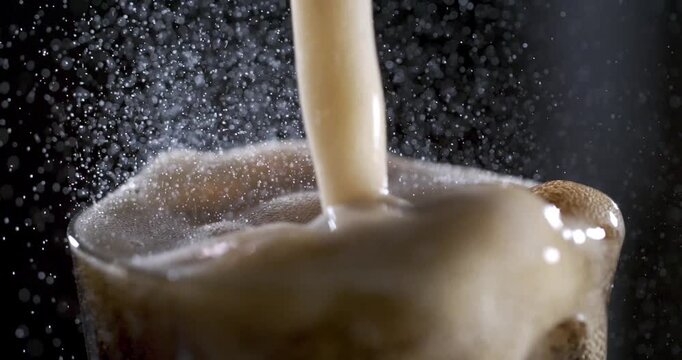 Slow motion close-up of beer pouring with bubbles and foam rising