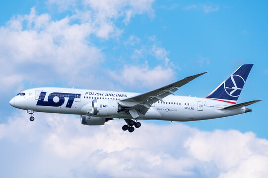 LOT Polish Airlines Boeing 787-8 Dreamliner passenger jet, registration SP-LRE, descending for landing against a blue sky with clouds.