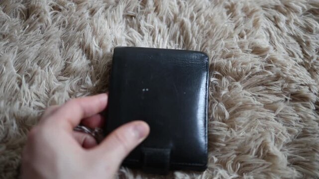Close up of a person preparing to secretly place a GPS tracker near a wallet illustrating covert surveillance privacy concerns unauthorized tracking and stalking risks
