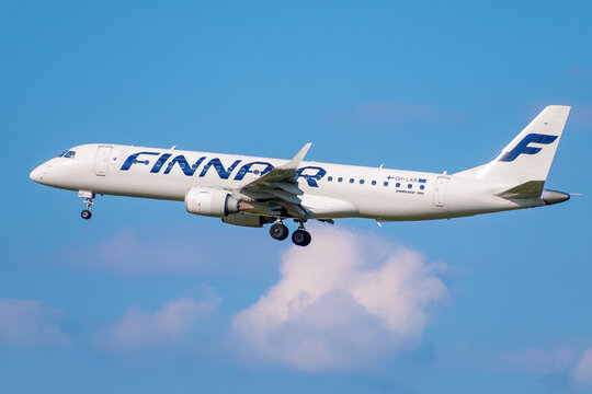 Finnair Embraer 190 passenger jet, registration OH-LKR, descending for landing against a blue sky with clouds.