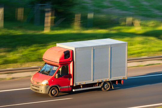 Red Delivery Van Cargo Box Truck Driving Fast on Motorway, The Concept of Express Delivery