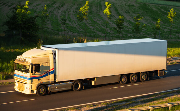 White Refrigerated Semi-Truck with Box Trailer Driving Along Highway Road, The Concept of Supply Chain
