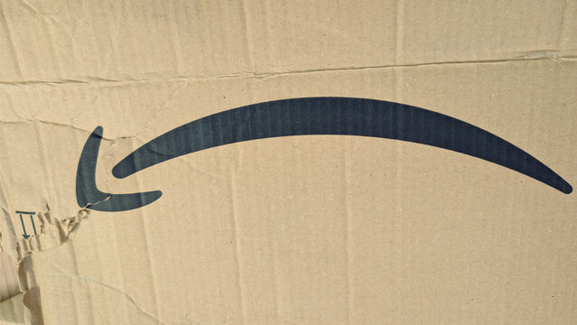 Leicester, England, UK - 12 June 2026: Amazon smile logo on cardboard box close up, texture of brown corrugated delivery package, e-commerce shipping backdrop
